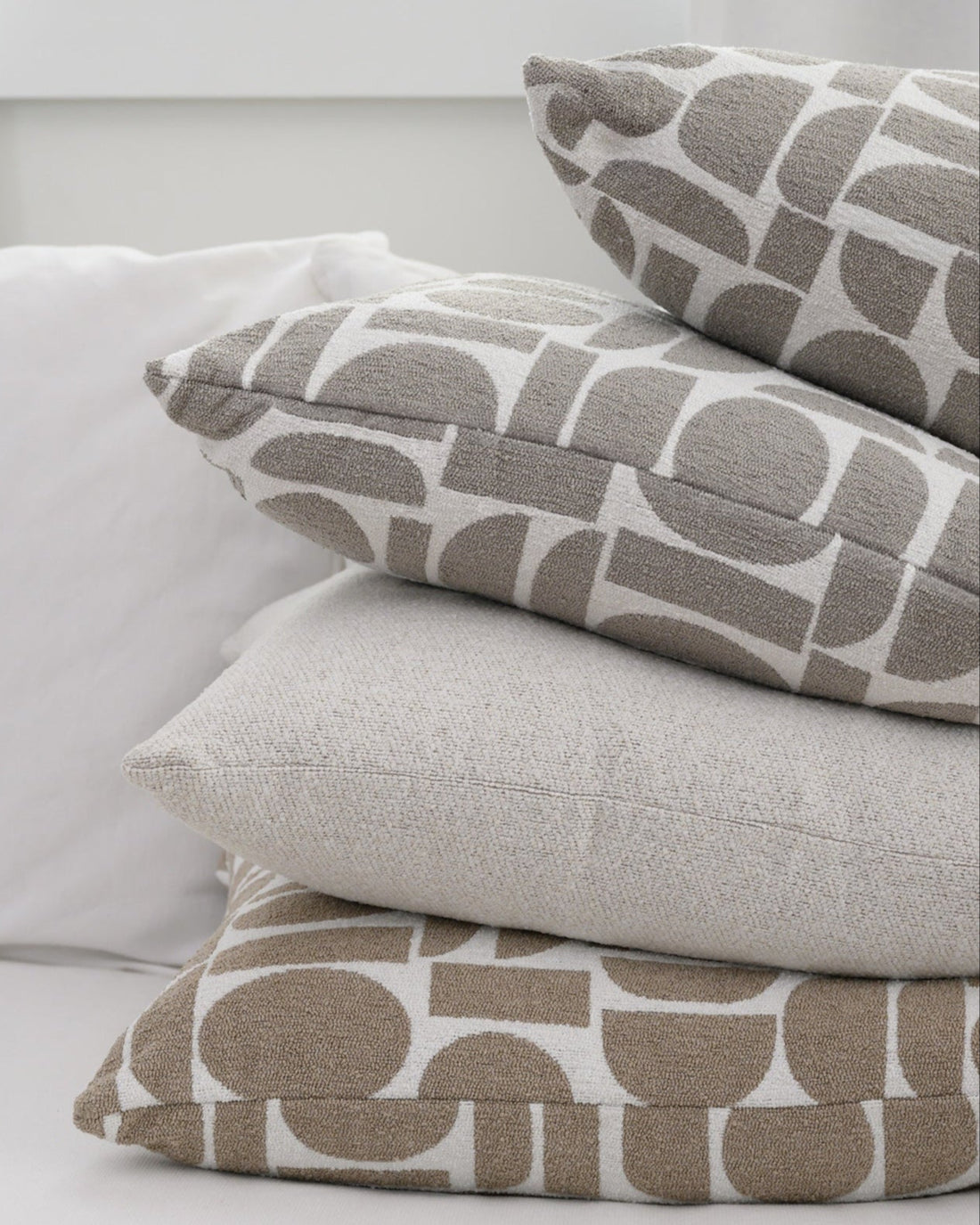 Chelsea Crescent cushions stacked together, showcasing the textured fabric and modern geometric design.