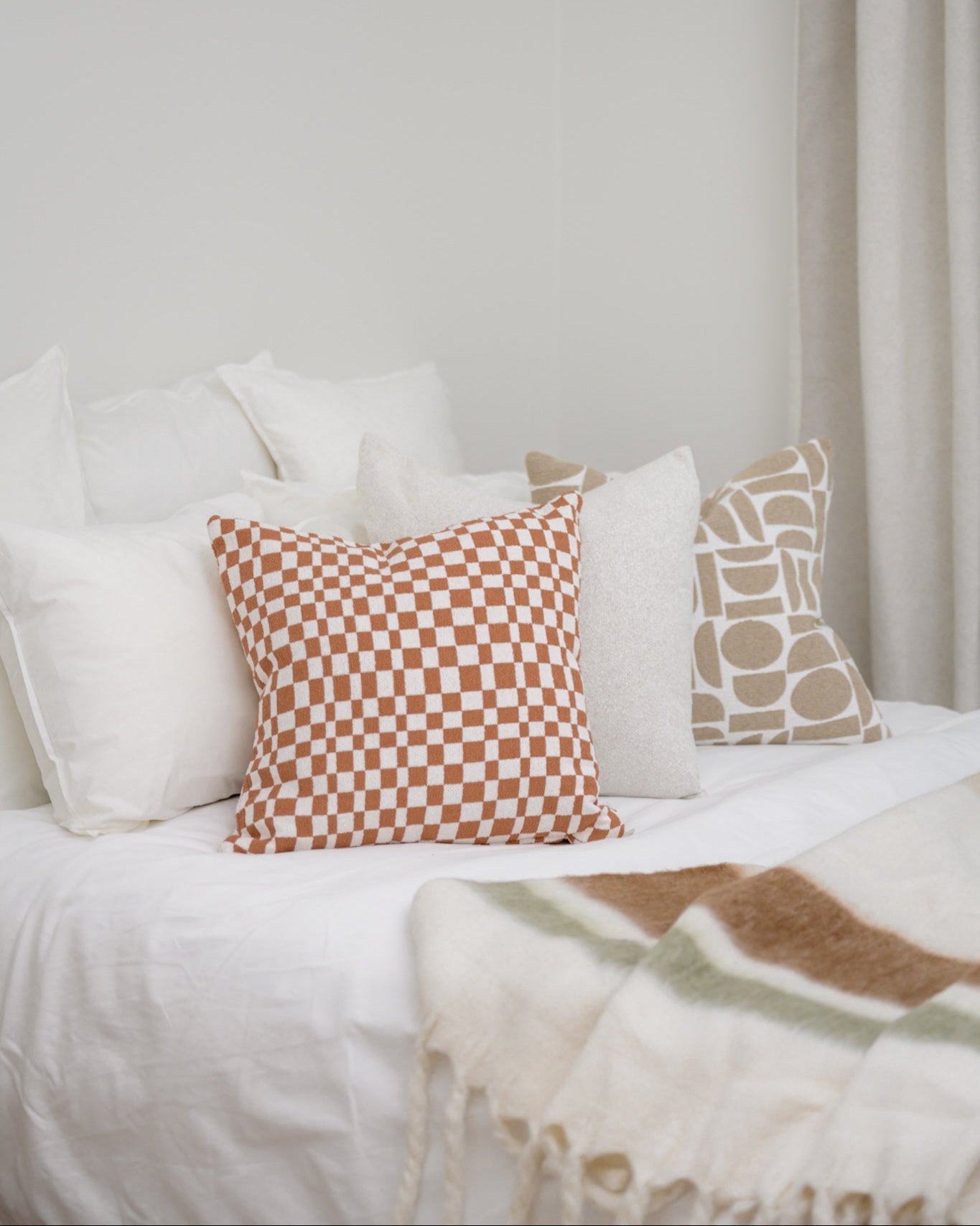 Bedroom styled with Chicago Check cushion in Terracotta and Chelsea Crescent cushion in Taupe, creating a warm, coordinated finish.