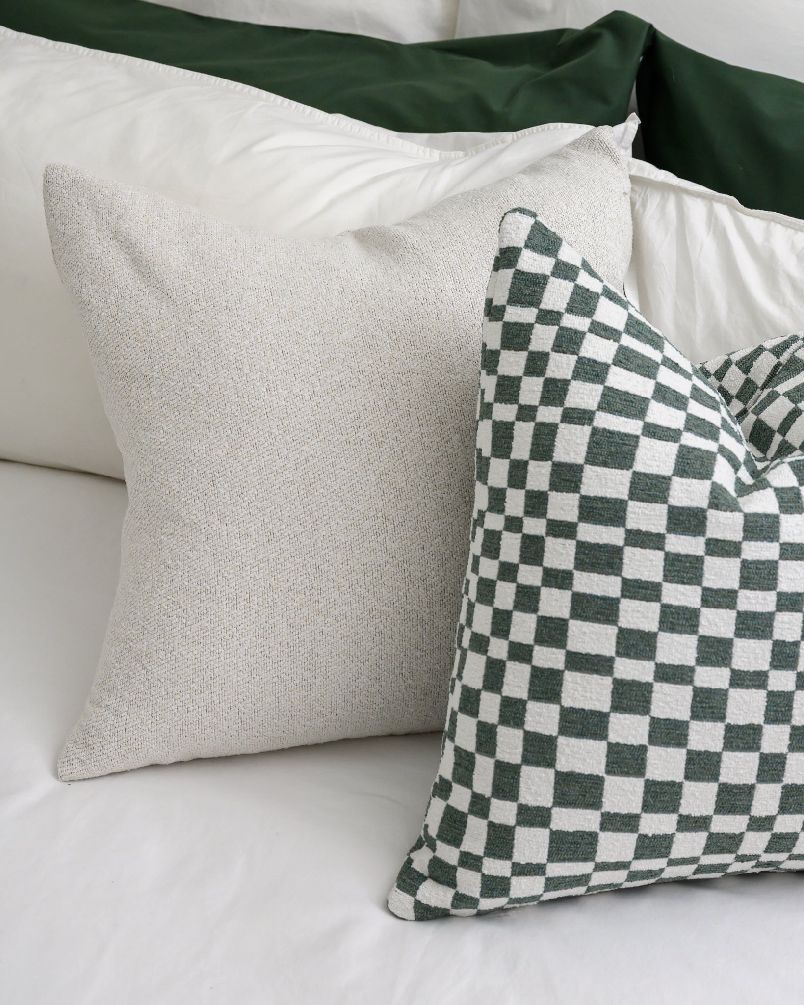 Close-up of Chicago Check cushion in Sage with Brooklyn Boucle cushion, showing the textured fabrics and plump feather and down inners.