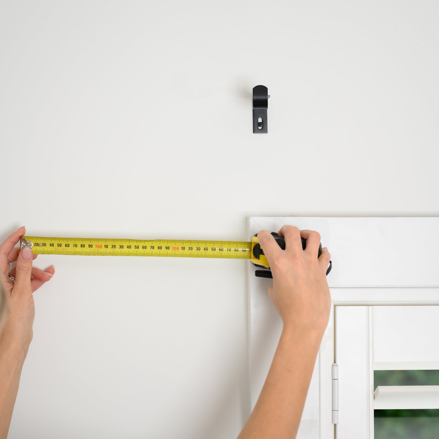 How to measure for your curtain rod width — showing the correct way to measure beyond the window frame for the perfect fit.