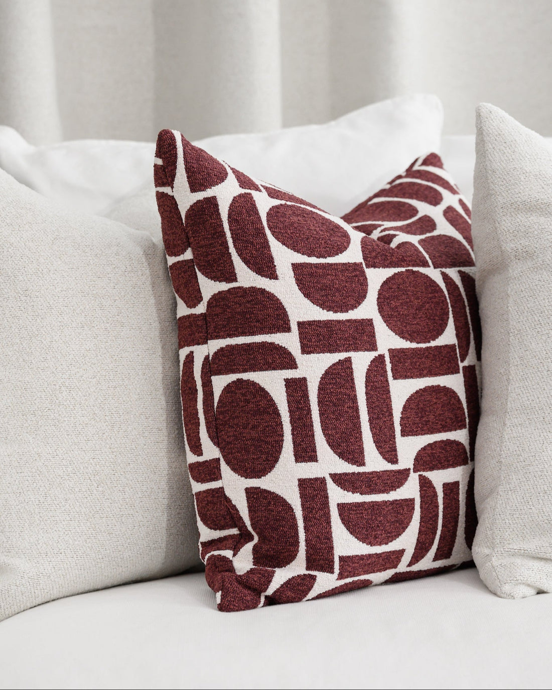 Chelsea Crescent cushion in burgundy styled with Brooklyn Boucle cushion, paired together for a cohesive designer look.