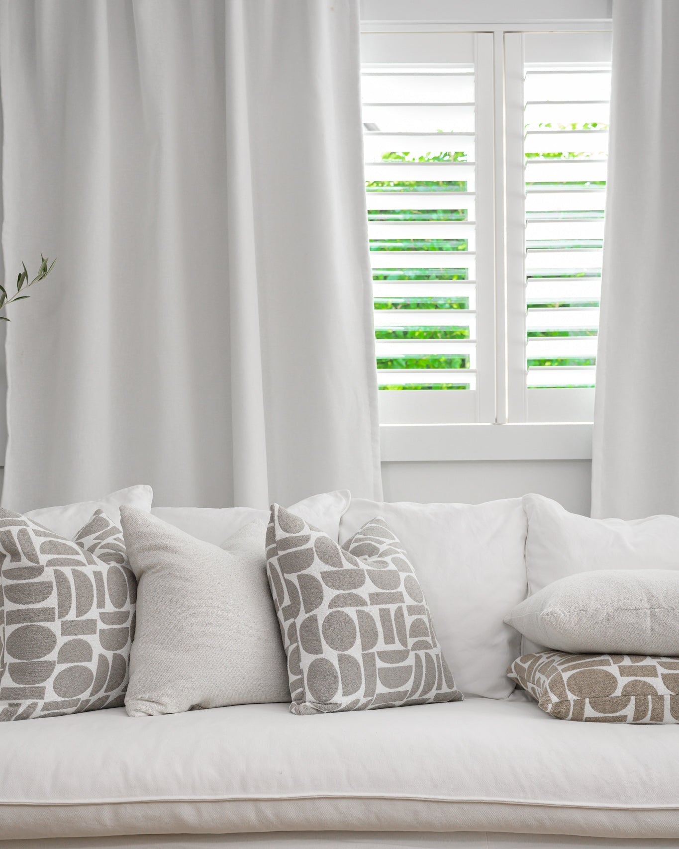 The Chelsea Crescent Feather & Down Filled Cushion styled on white couch.