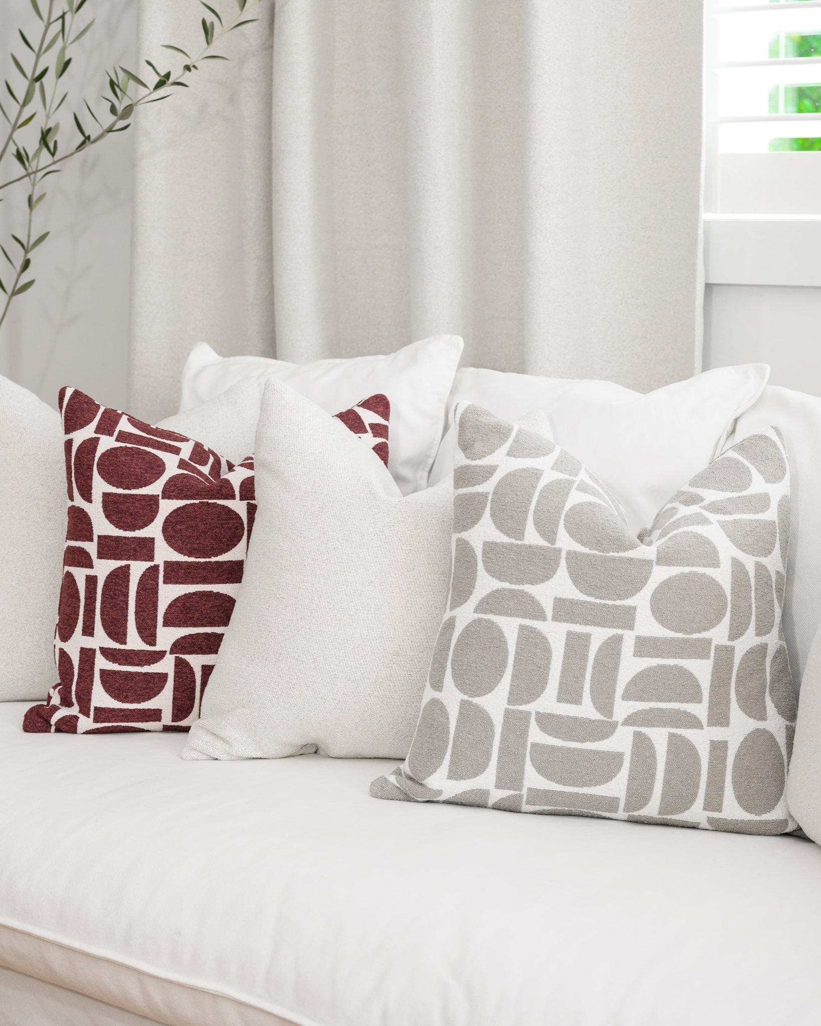 Chelsea Crescent cushions in burgundy and dove grey styled with a Brooklyn Boucle cushion, creating a cohesive designer look.
