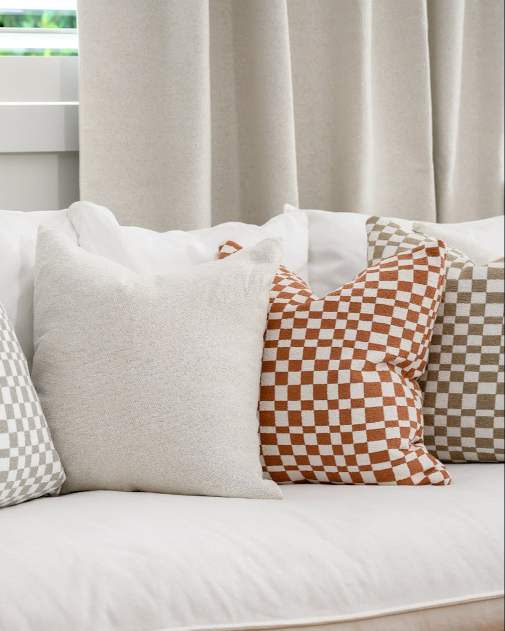 Chicago Check cushions in Terracotta and Taupe styled with a Brooklyn Boucle cushion, creating a cohesive designer look.