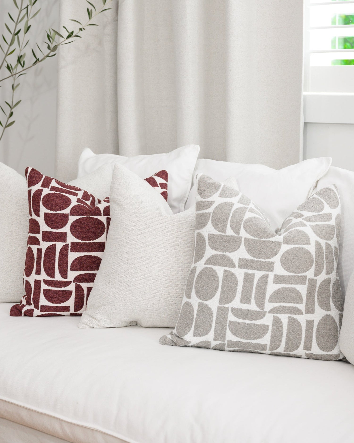 Chelsea Crescent cushions in burgundy and dove grey styled with a Brooklyn Boucle cushion, creating a cohesive designer look.