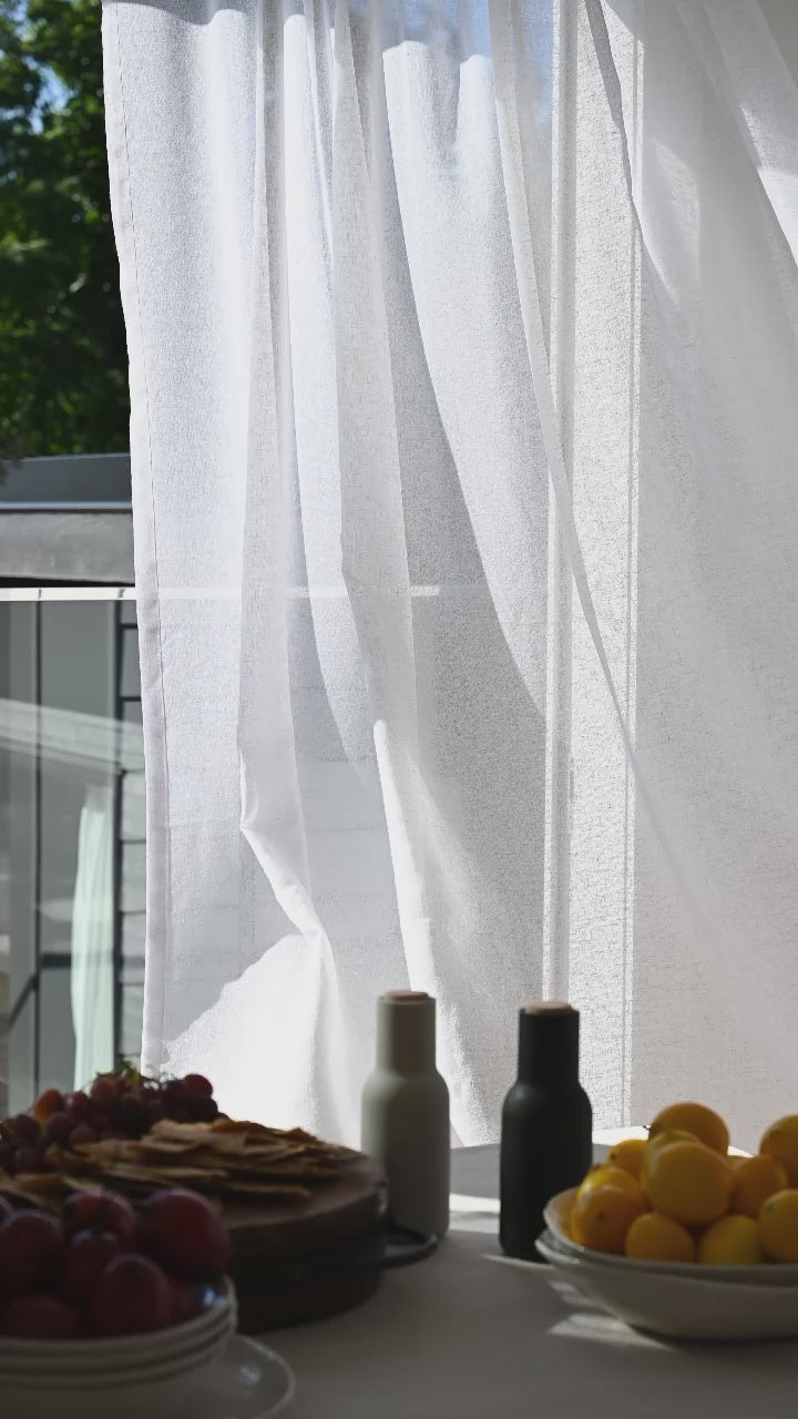The Soho Sheer linen curtain gently blowing in the breeze, showcasing its beautiful texture and natural drape.